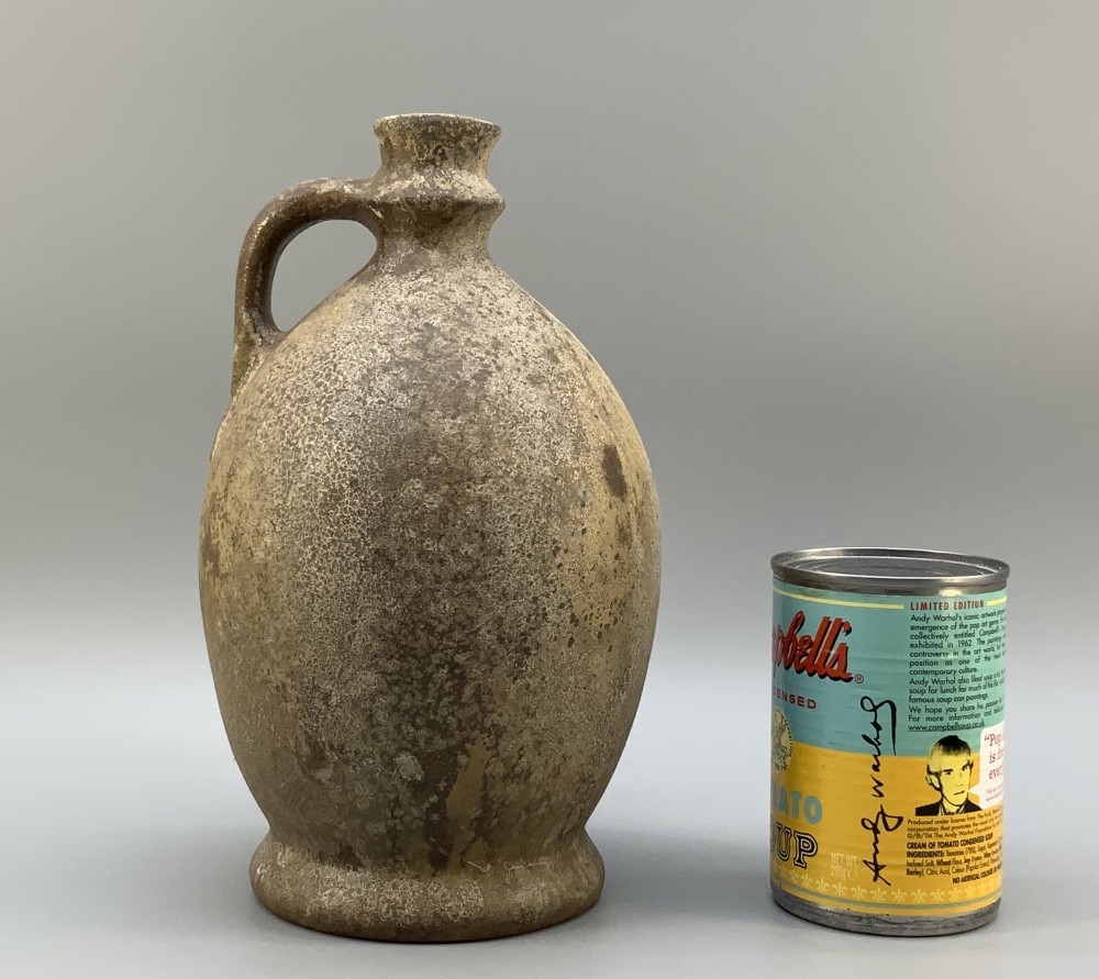 A 19th-century salt-glazed stoneware flagon featuring a mottled brown textured surface, narrow neck, flared rim, and a single loop handle. View III