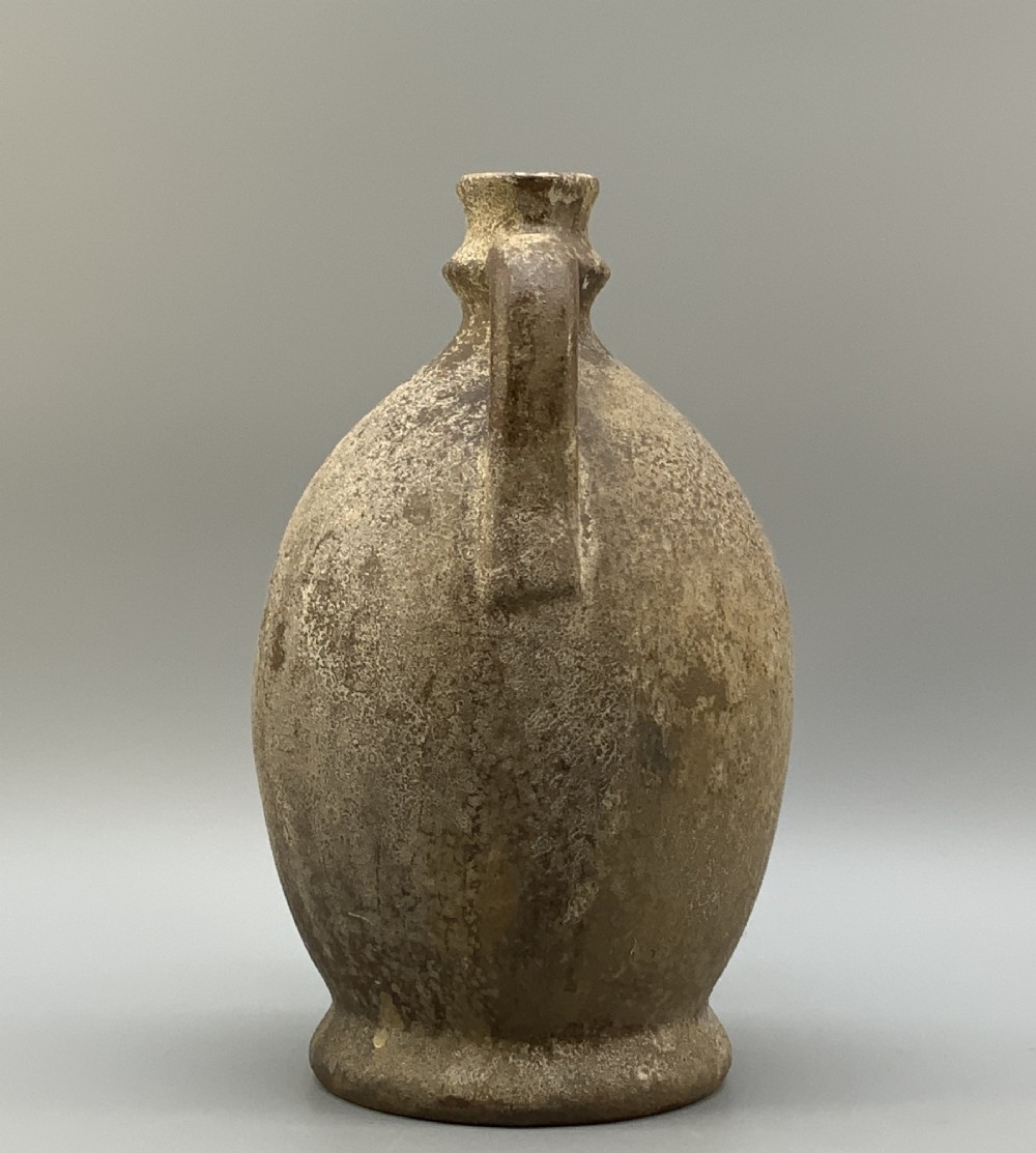 A 19th-century salt-glazed stoneware flagon featuring a mottled brown textured surface, narrow neck, flared rim, and a single loop handle. View V