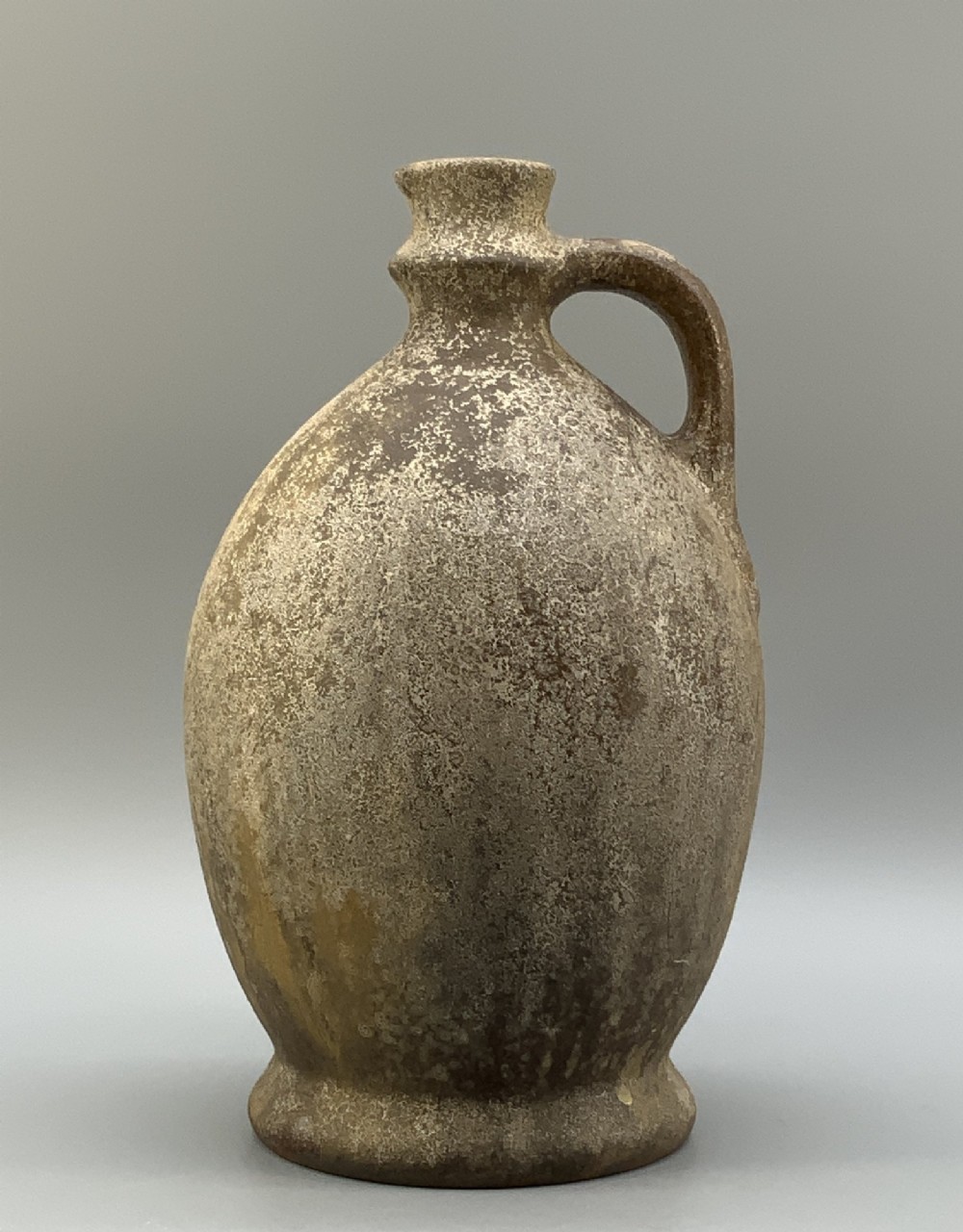 A 19th-century salt-glazed stoneware flagon featuring a mottled brown textured surface, narrow neck, flared rim, and a single loop handle. View VIII