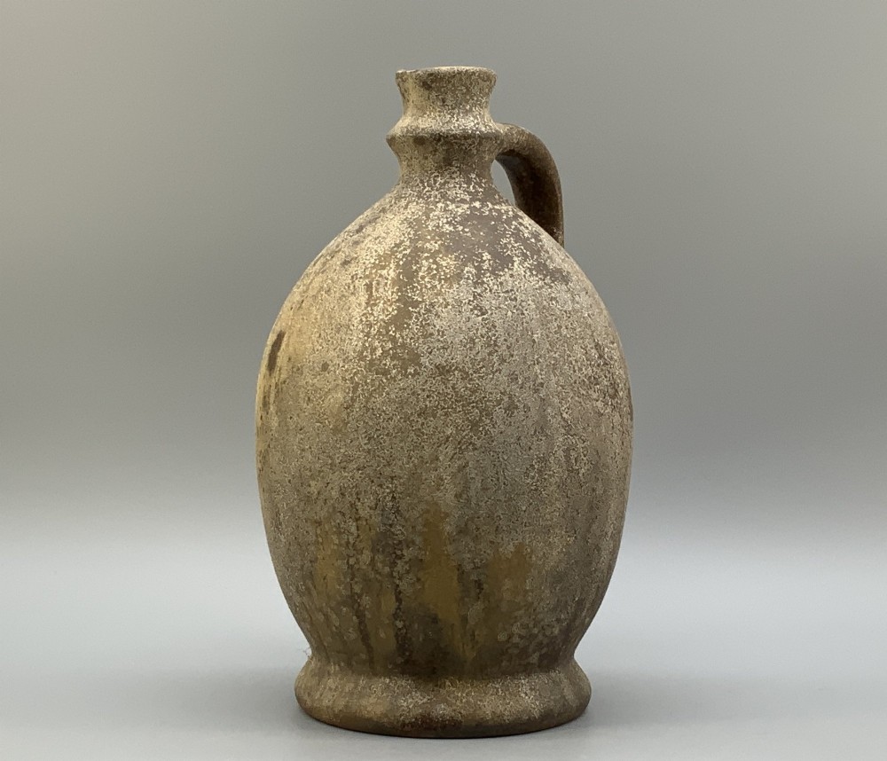 A 19th-century salt-glazed stoneware flagon featuring a mottled brown textured surface, narrow neck, flared rim, and a single loop handle. View IX