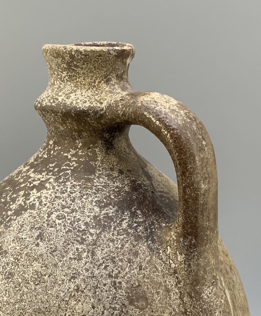 A 19th-century salt-glazed stoneware flagon featuring a mottled brown textured surface, narrow neck, flared rim, and a single loop handle. View X