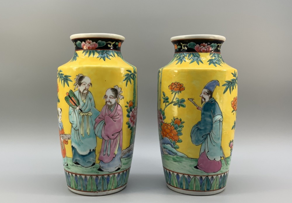A pair of yellow ground Chinese porcelain vases decorated with painted figures, floral motifs, and green leaf borders around the base. View II