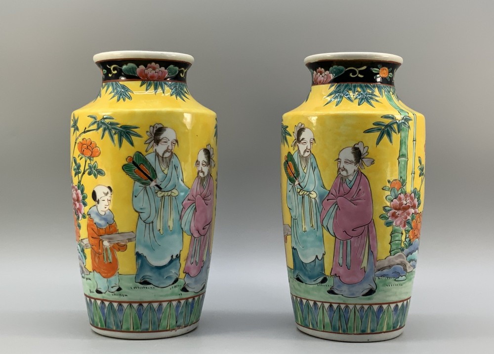 A pair of yellow ground Chinese porcelain vases decorated with painted figures, floral motifs, and green leaf borders around the base. View IV