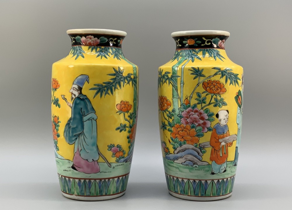 A pair of yellow ground Chinese porcelain vases decorated with painted figures, floral motifs, and green leaf borders around the base. View V