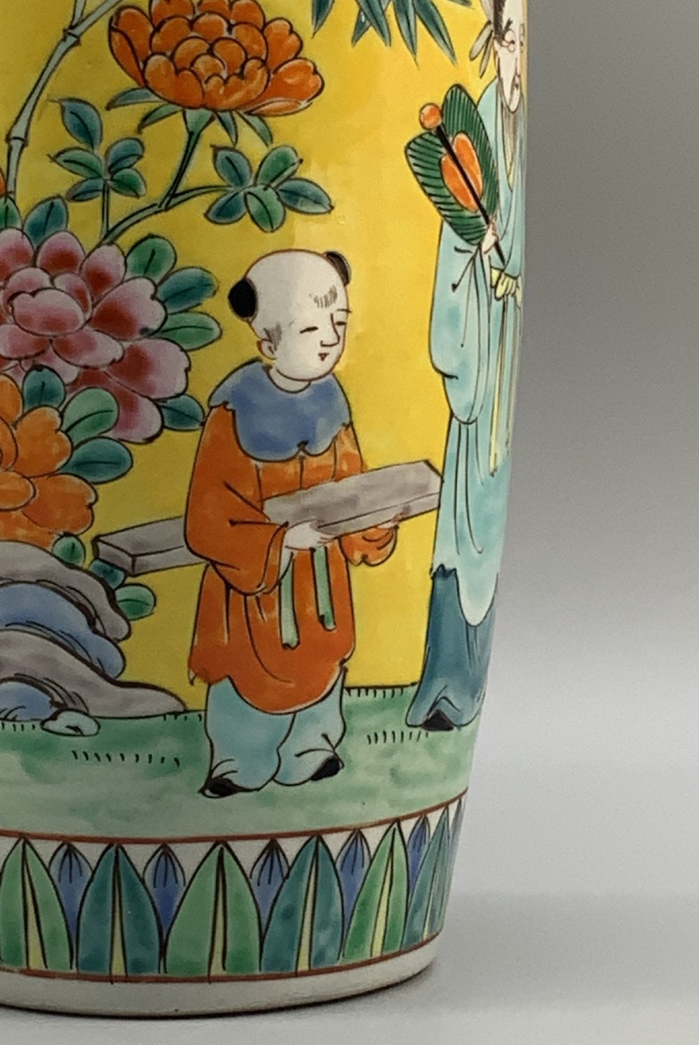 A pair of yellow ground Chinese porcelain vases decorated with painted figures, floral motifs, and green leaf borders around the base. View VII