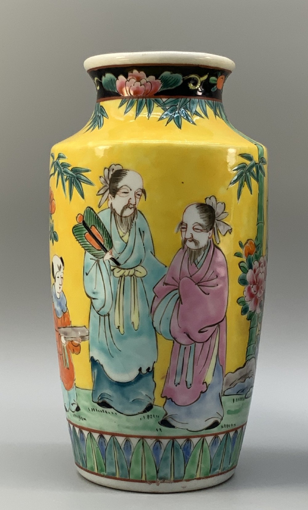 A pair of yellow ground Chinese porcelain vases decorated with painted figures, floral motifs, and green leaf borders around the base. View IX