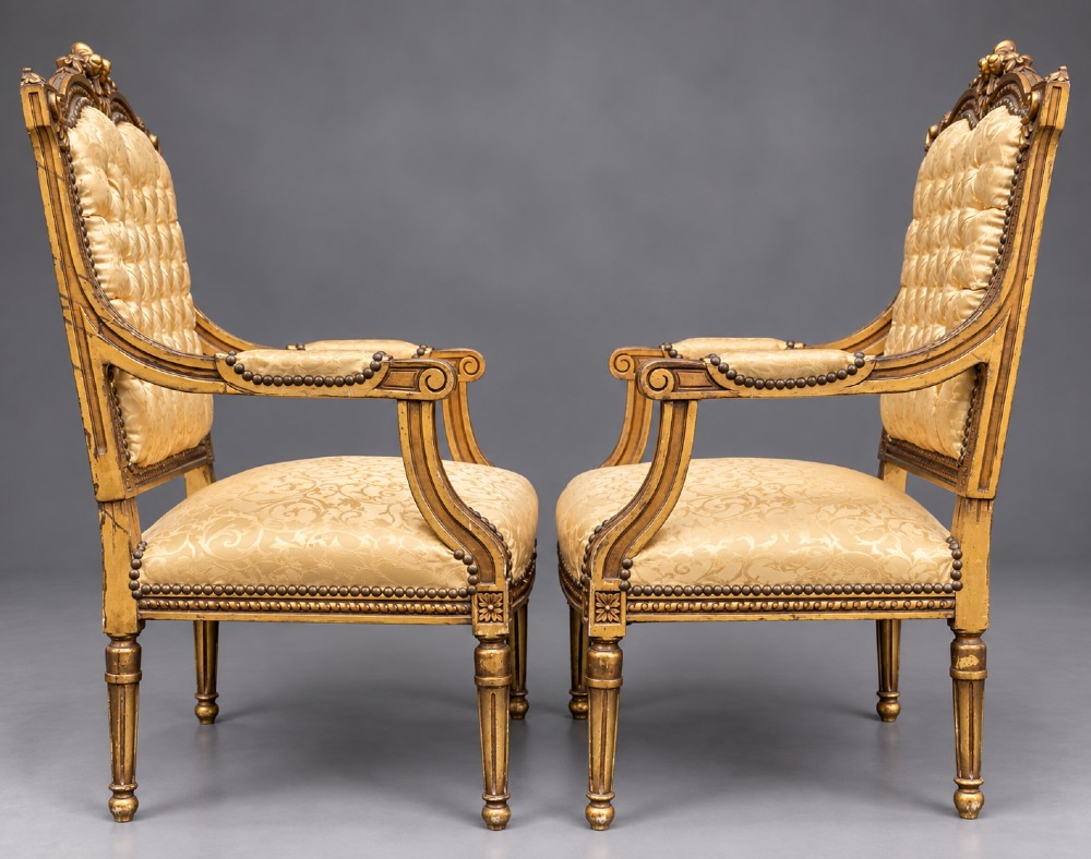 A pair of 19th-century giltwood open armchairs featuring carved leaf detailing, button-tufted gold damask upholstery, and fluted front legs. View III
