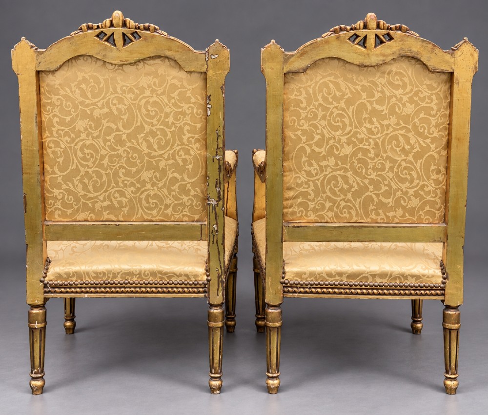 A pair of 19th-century giltwood open armchairs featuring carved leaf detailing, button-tufted gold damask upholstery, and fluted front legs. View V