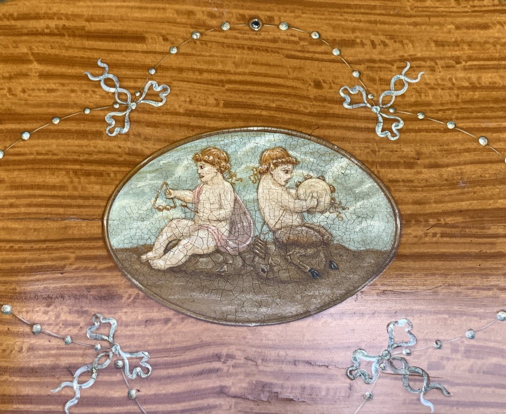 An oval satinwood sewing table featuring hand-painted floral swags, slender tapered legs, an X-form stretcher, and a pleated light blue fabric work basket suspended below. View IX