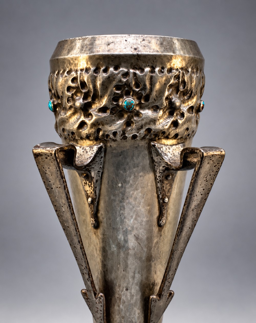 An Arts and Crafts hammered pewter vase featuring raised geometric support fins, a textured upper band, and inlaid turquoise cabochons. View V