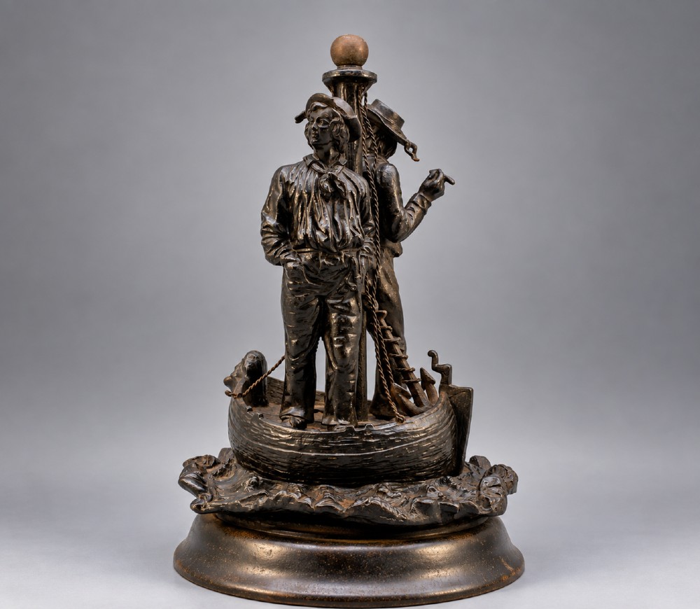 A nineteenth-century dark patinated bronze sculpture depicting two fishermen standing in a small vessel atop sculpted ocean waves, mounted on a rounded base. View III