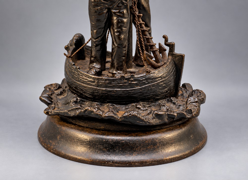 A nineteenth-century dark patinated bronze sculpture depicting two fishermen standing in a small vessel atop sculpted ocean waves, mounted on a rounded base. View IV