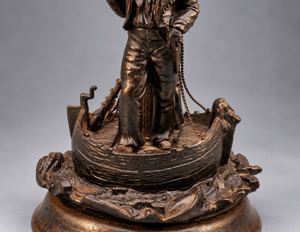 A nineteenth-century dark patinated bronze sculpture depicting two fishermen standing in a small vessel atop sculpted ocean waves, mounted on a rounded base. View VII