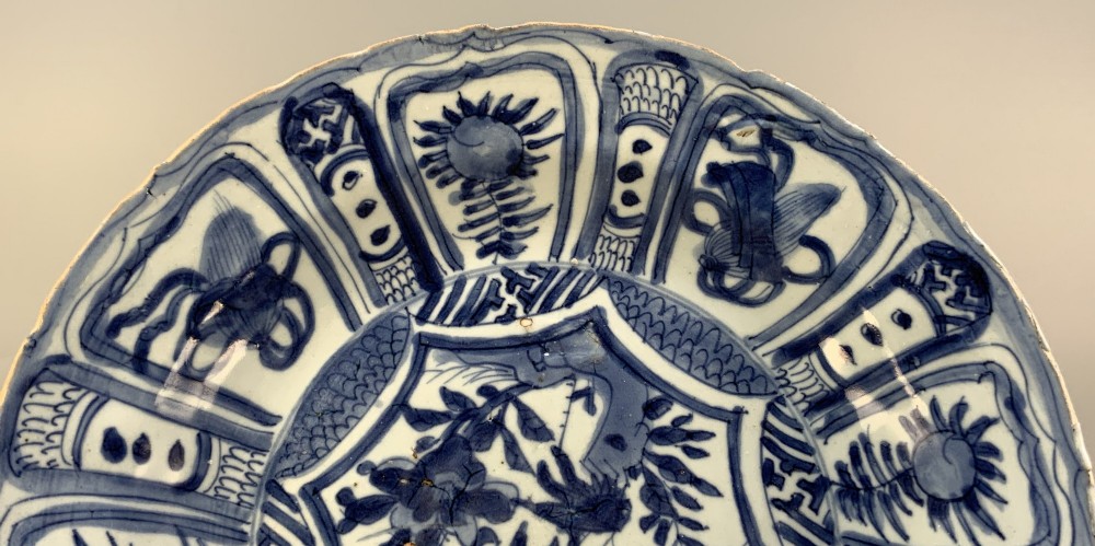 A late 16th-century Chinese Kraak blue and white porcelain charger with panelled floral motifs, shown displayed alongside detached rim fragments. View V