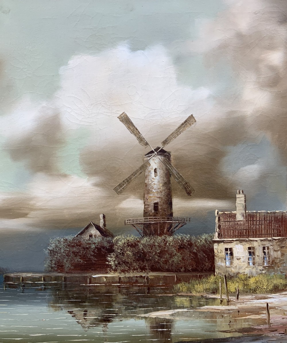 A horizontal oil painting depicting Dutch windmills and stone buildings along a riverbank under a cloudy sky, presented in an ornate gilt frame. View V