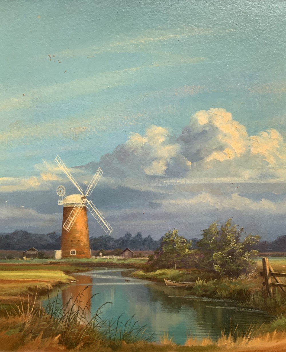 An oil painting depicting Horsey Mill set amidst the Norfolk Broads under a cloud-filled sky, presented in an elaborate gilded swept frame. View VI