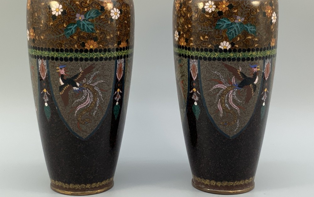 A pair of Japanese Meiji period cloisonne enamel vases featuring detailed phoenix birds, floral motifs, and geometric borders on a dark background. View V