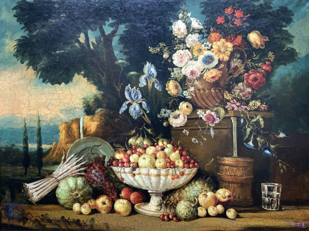 A classical oil painting displaying a bowl of fruit, a urn with flowers, asparagus, and melons set against a dark landscape backdrop within a carved silver-grey frame. View III