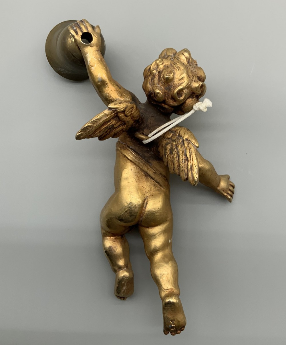 A set of three gilt metal wall sconces crafted in the shape of winged cherubs holding bell-shaped light sockets. View VI