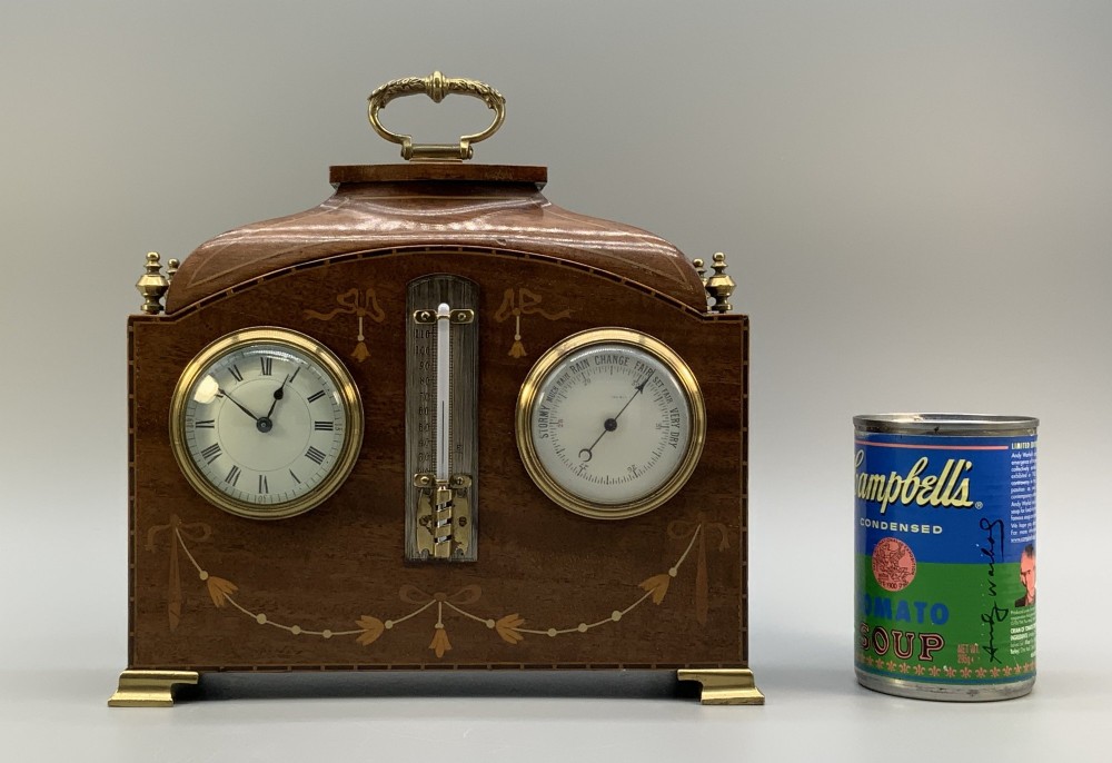 An Edwardian mahogany desk compendium featuring an inlaid floral swag motif, central thermometer, clock dial, barometer dial, and top brass handle. View II