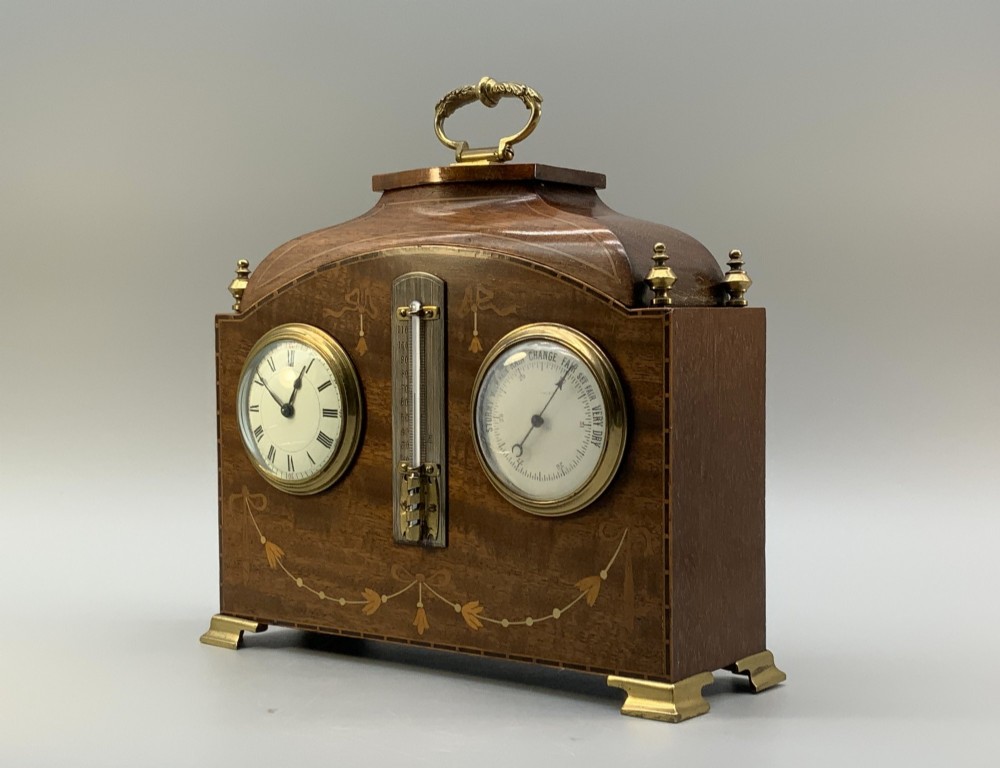 An Edwardian mahogany desk compendium featuring an inlaid floral swag motif, central thermometer, clock dial, barometer dial, and top brass handle. View III