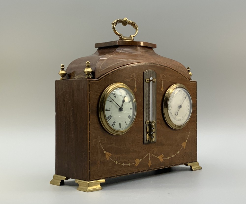 An Edwardian mahogany desk compendium featuring an inlaid floral swag motif, central thermometer, clock dial, barometer dial, and top brass handle. View IV