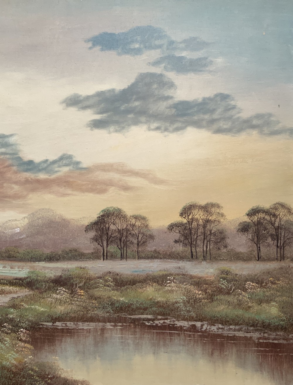 A twentieth-century framed oil painting depicting a countryside path alongside a reflective pond, surrounded by tall trees and distant hills under a clouded sky. View VI