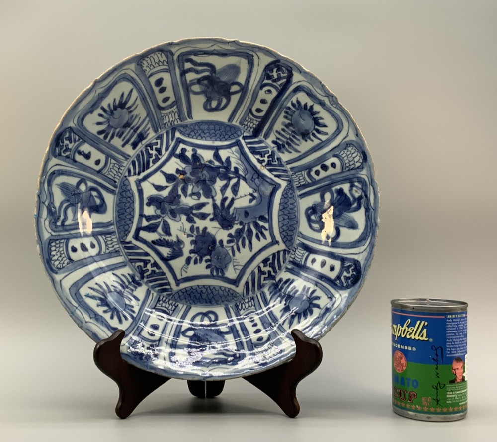 A circular 16th-century Chinese Kraak porcelain charger decorated in cobalt blue underglaze featuring a central floral scene surrounded by a panelled foliate rim. View II