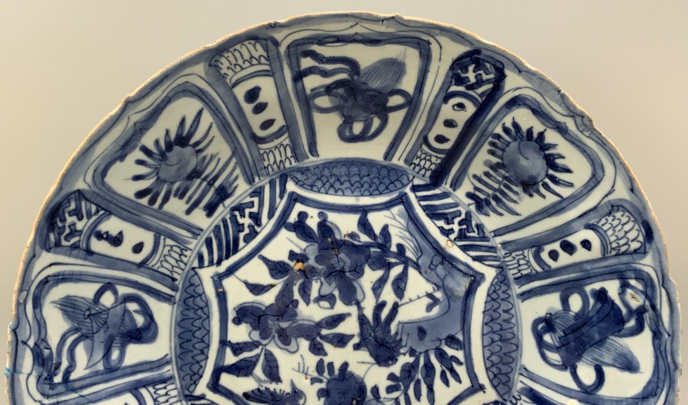 A circular 16th-century Chinese Kraak porcelain charger decorated in cobalt blue underglaze featuring a central floral scene surrounded by a panelled foliate rim. View III