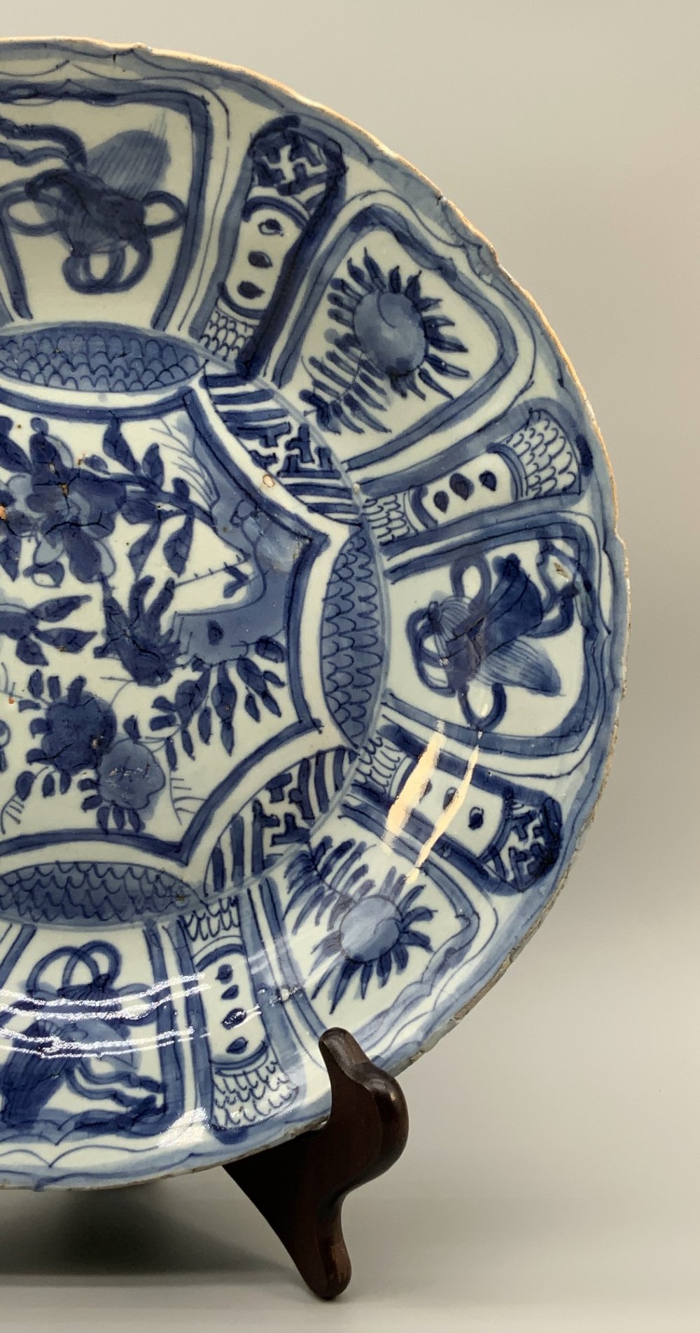 A circular 16th-century Chinese Kraak porcelain charger decorated in cobalt blue underglaze featuring a central floral scene surrounded by a panelled foliate rim. View V