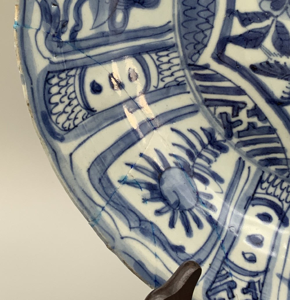 A circular 16th-century Chinese Kraak porcelain charger decorated in cobalt blue underglaze featuring a central floral scene surrounded by a panelled foliate rim. View VII