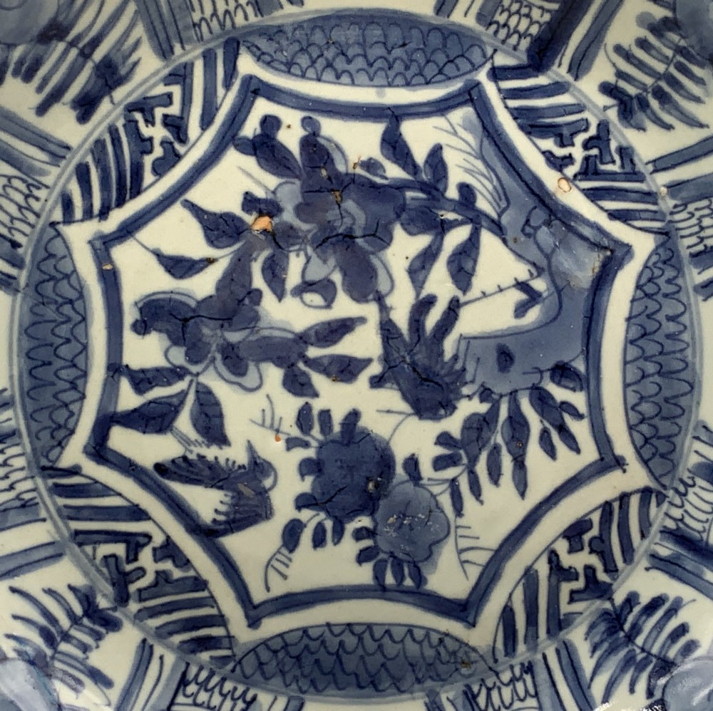 A circular 16th-century Chinese Kraak porcelain charger decorated in cobalt blue underglaze featuring a central floral scene surrounded by a panelled foliate rim. View VIII