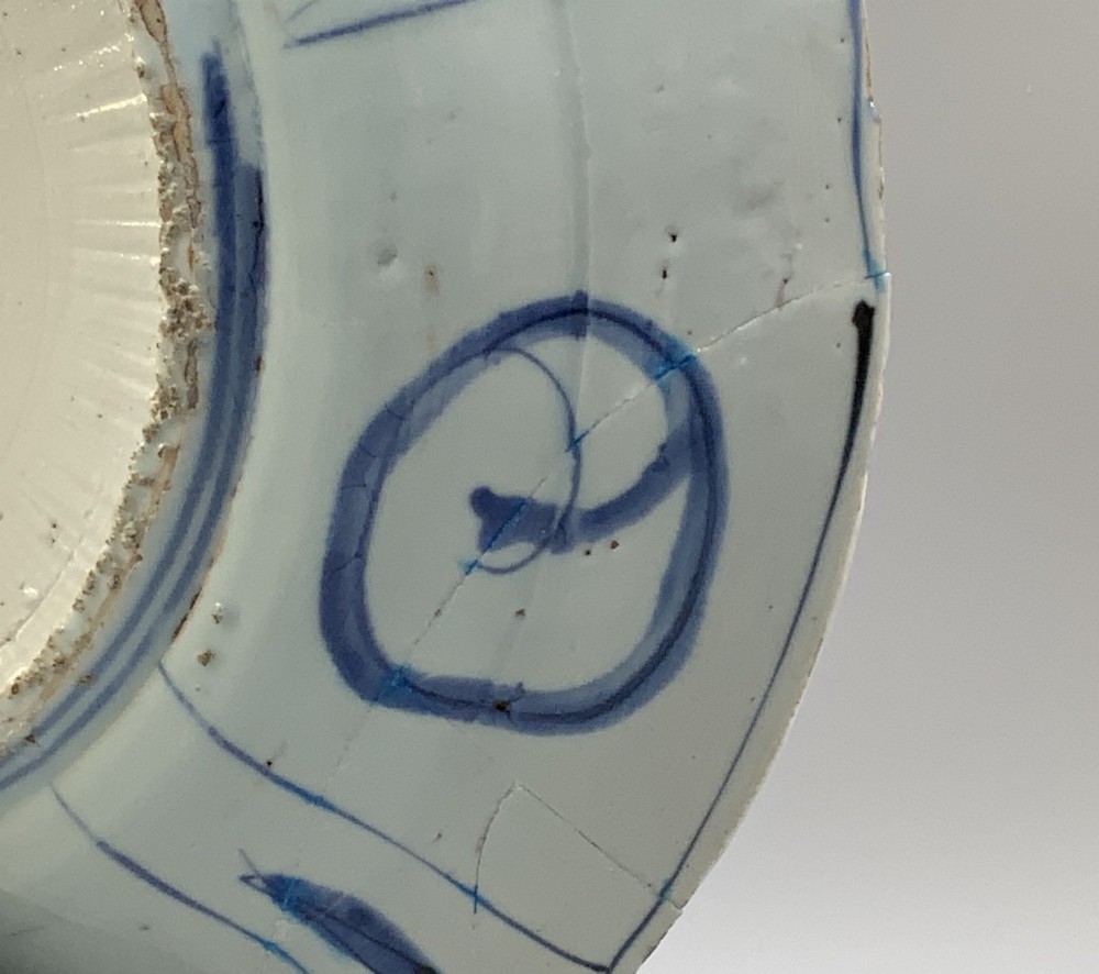 A circular 16th-century Chinese Kraak porcelain charger decorated in cobalt blue underglaze featuring a central floral scene surrounded by a panelled foliate rim. View XIII