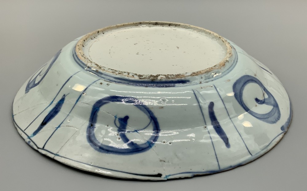 A circular 16th-century Chinese Kraak porcelain charger decorated in cobalt blue underglaze featuring a central floral scene surrounded by a panelled foliate rim. View XIV