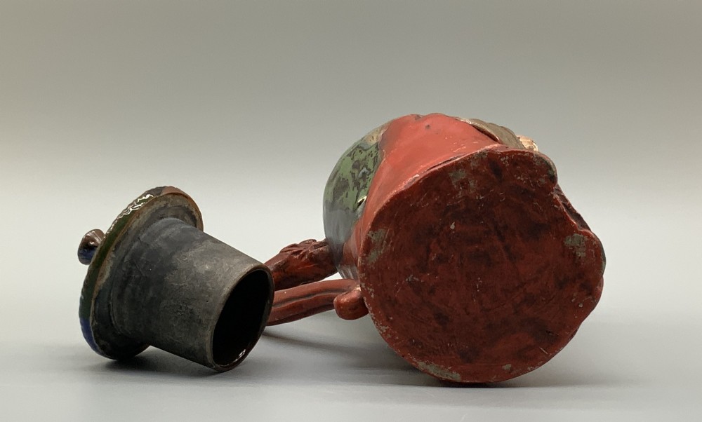 An antique Japanese Sumida Gawa lidded pottery jug sculpted in the form of a robed figure with red attire, green glaze drips, and a matching fitted lid. View XIV