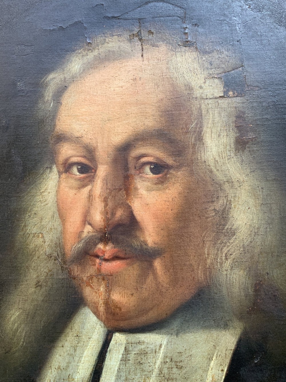An oval 17th-century oil painting depicting a gentleman with grey hair, a moustache, and white falling bands collar in a carved gold frame. View VI