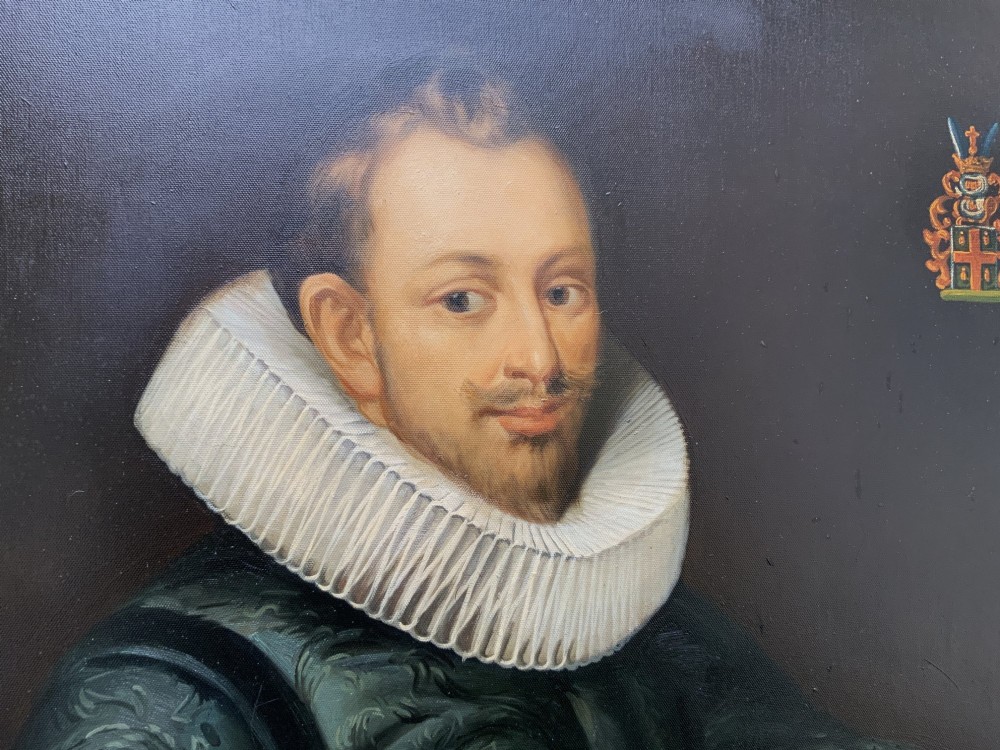 A full-length oil painting depicting a 17th-century gentleman in a dark doublet and white ruff collar, set within a black and gold frame. View XII
