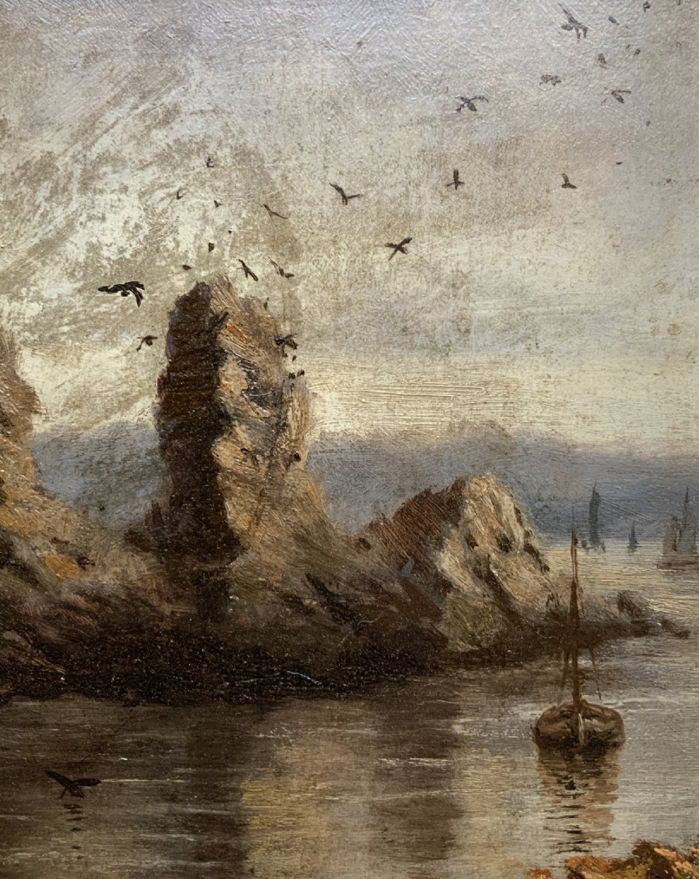 A 19th-century miniature oil painting depicting a coastal cliff scene with a prominent rock stack, small boats, and birds in flight, set within a dark wooden frame. View III