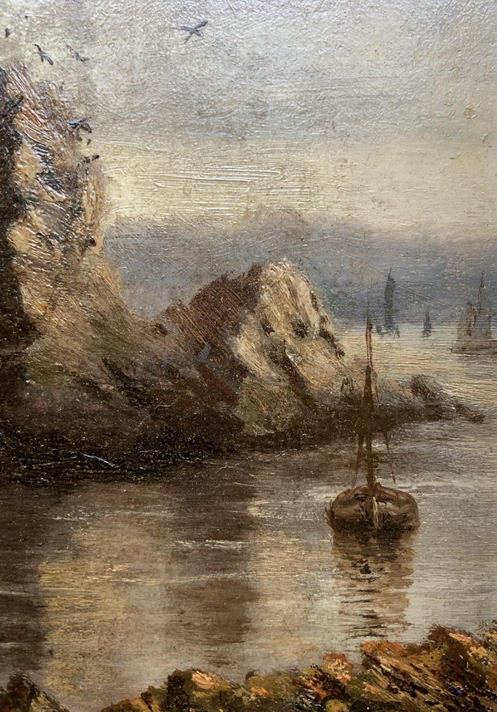 A 19th-century miniature oil painting depicting a coastal cliff scene with a prominent rock stack, small boats, and birds in flight, set within a dark wooden frame. View VIII