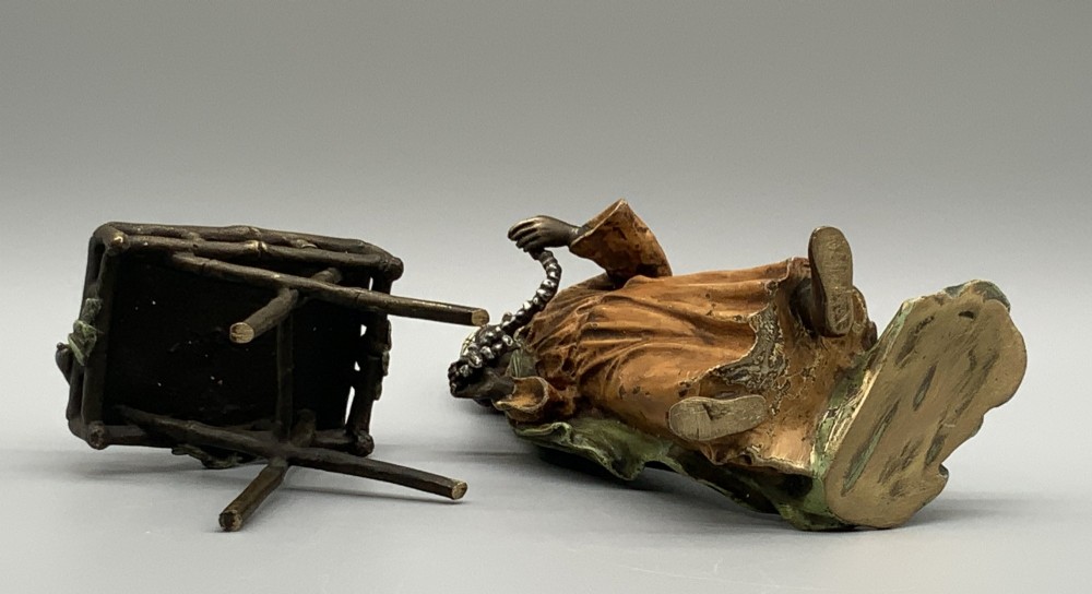 A cold-painted bronze Orientalist figure wearing a turban and ochre robe, standing next to a small table displaying wares. View XIII