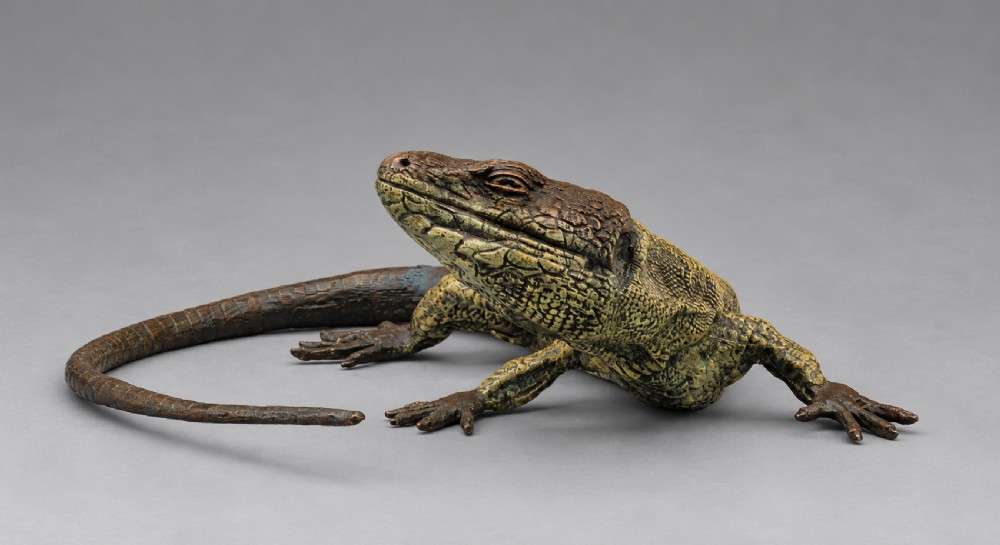 An antique cold-painted bronze sculpture depicting a realistic lizard with textured yellow and brown skin, blue accents, and a long curved tail. View II