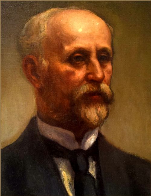 fig 1. An oil painting on canvas depicting a gentleman with a grey moustache and beard wearing a dark formal suit jacket and tie.