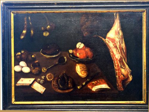 fig 4. A 17th-century Spanish Baroque oil painting depicting a tabletop larder scene with meat, eggs, walnuts, bread, dice, playing cards, and utensils against a dark background.