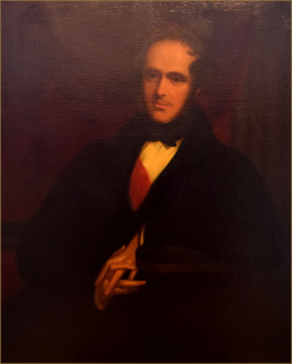 A 19th-century oil painting depicting a gentleman in dark attire wearing a red sash and bow tie against a dark background.