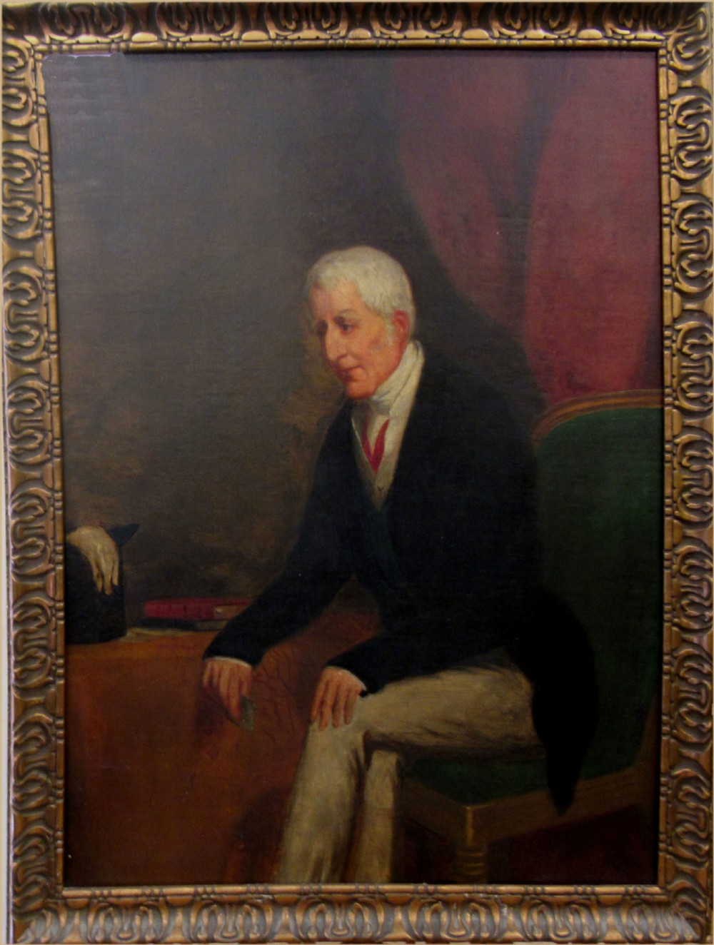 An oil painting depiction of an elderly gentleman in a dark tailcoat seated sideways on a green upholstered chair against a dark red drapery backdrop. View V