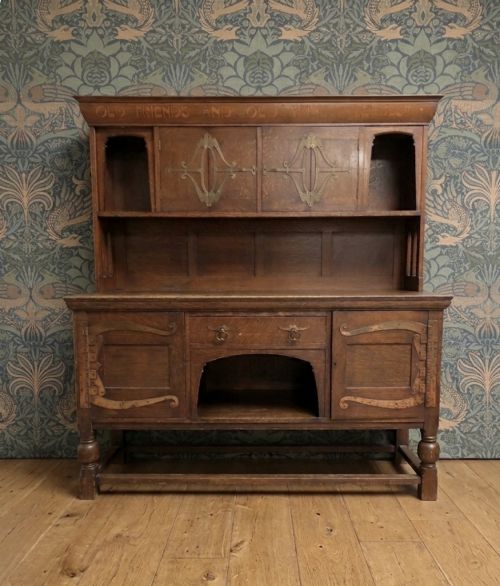 fig 1. A solid oak Arts and Crafts sideboard with an inscribed upper cornice, leaded glazed doors, open central niche, and long decorative iron hinges.