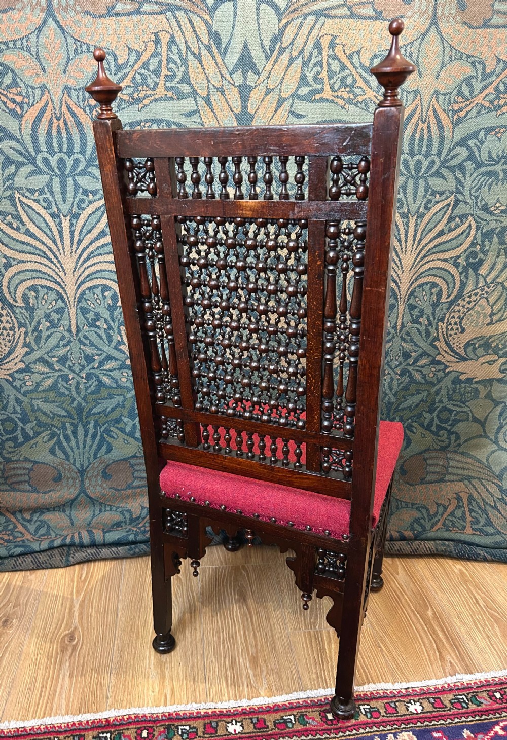 A pair of dark wood Cairene side chairs featuring turned bobbin mashrabiya latticework on the backrests and lower aprons, topped with corner finials and fitted with red wool upholstered seats. View III