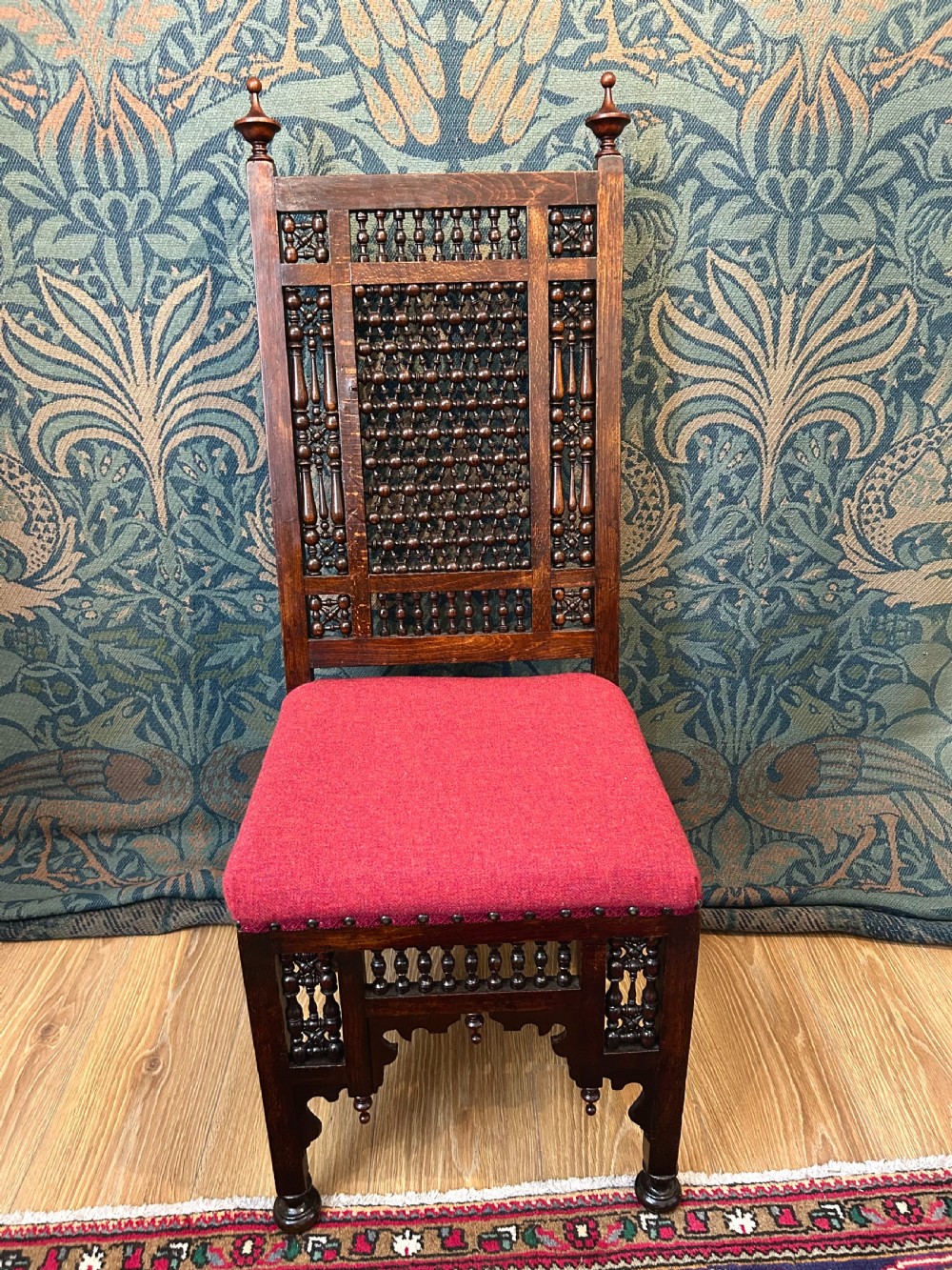 A pair of dark wood Cairene side chairs featuring turned bobbin mashrabiya latticework on the backrests and lower aprons, topped with corner finials and fitted with red wool upholstered seats. View V