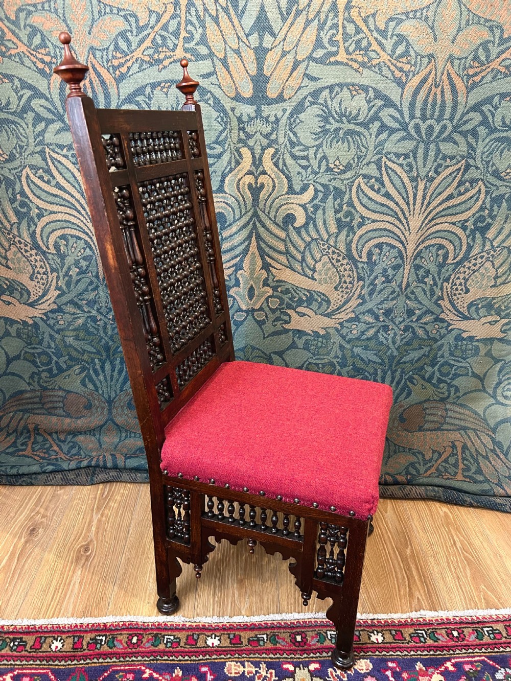 A pair of dark wood Cairene side chairs featuring turned bobbin mashrabiya latticework on the backrests and lower aprons, topped with corner finials and fitted with red wool upholstered seats. View VII