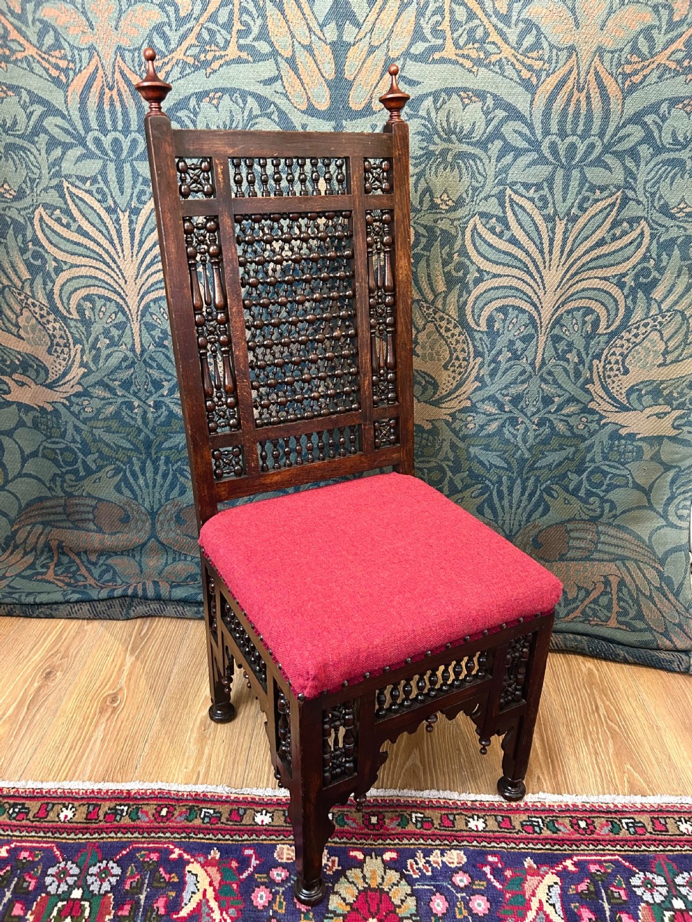 A pair of dark wood Cairene side chairs featuring turned bobbin mashrabiya latticework on the backrests and lower aprons, topped with corner finials and fitted with red wool upholstered seats. View VIII